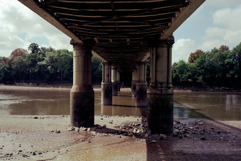 a concrete structure stands in the middle of a river under a bridge