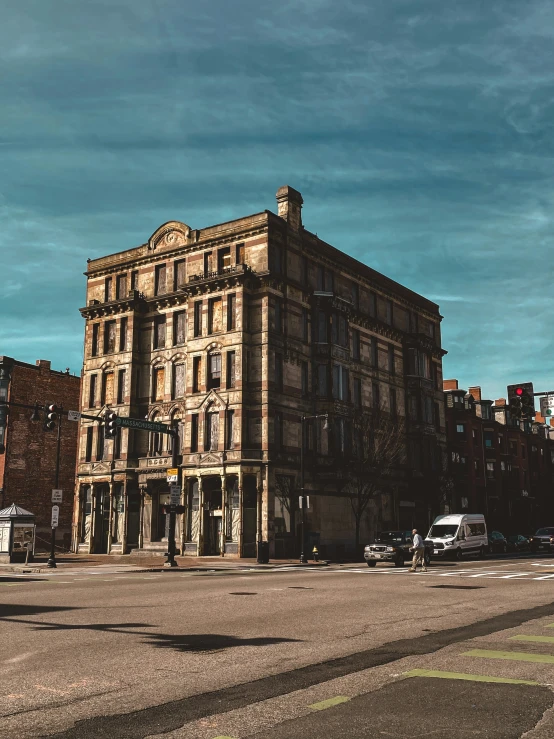 a very big old brick building with cars driving by