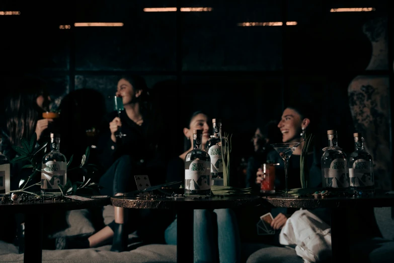 people sitting on couches around table with empty bottles on it