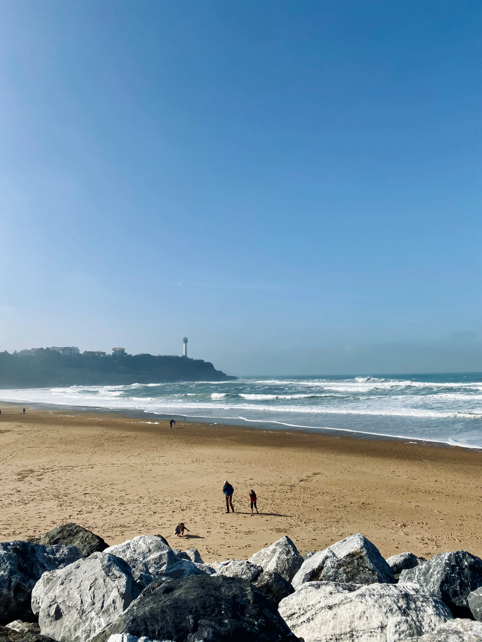 two people are on the beach and one is flying a kite