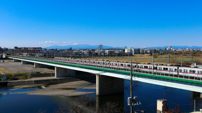 the commuter train rides across a bridge with tall buildings behind