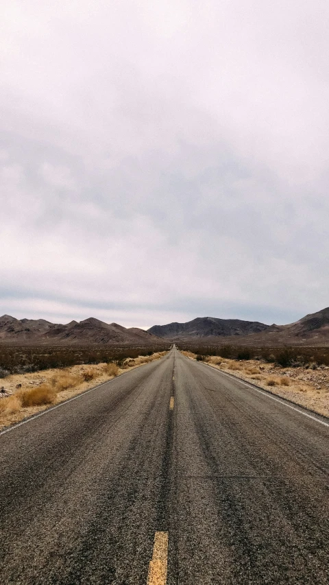 a long road stretches across the plain with mountains in the background