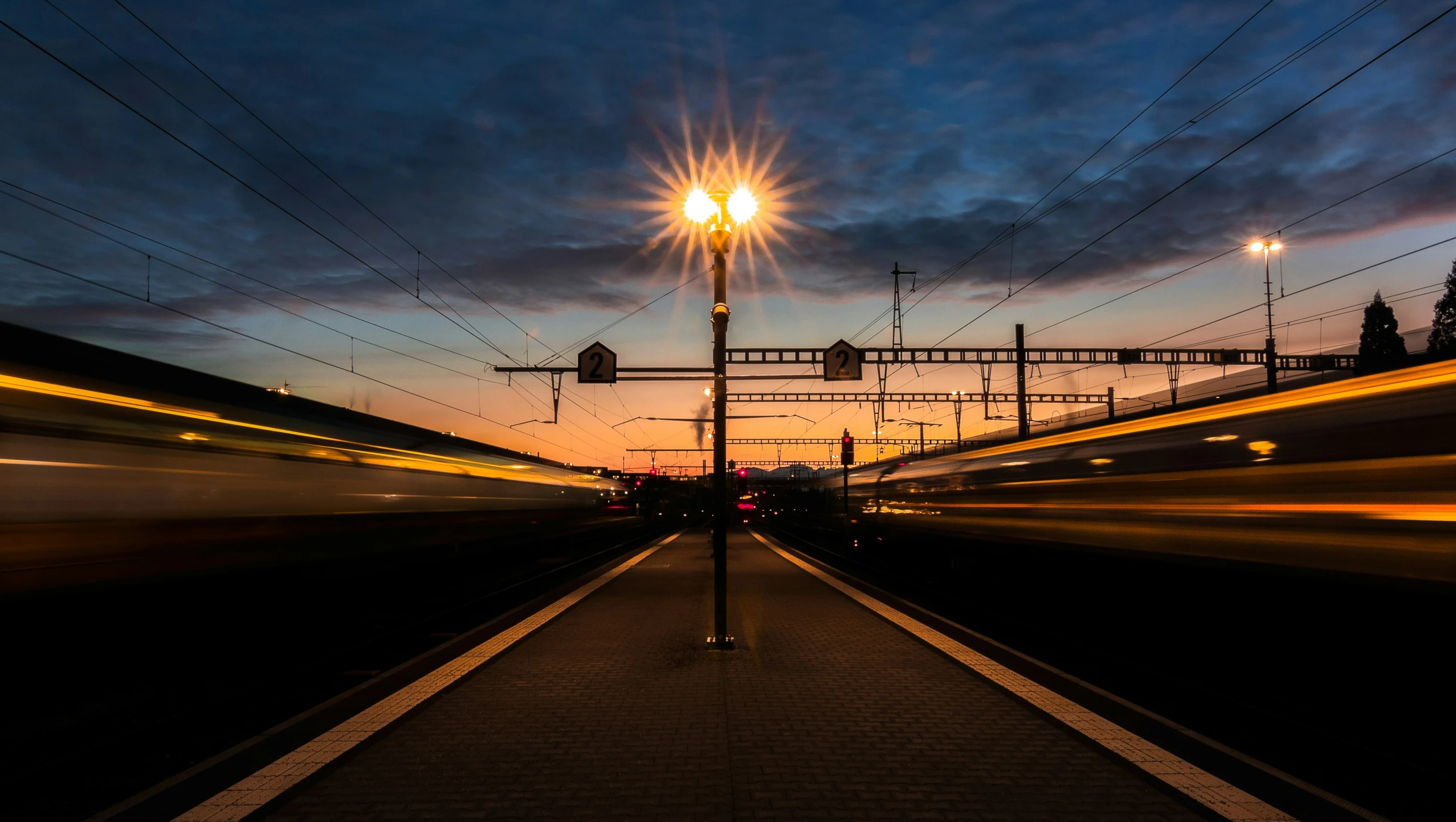 an empty platform with wires hanging above and passing cars