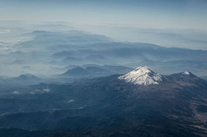 view from airplane looking over mountains in the blue