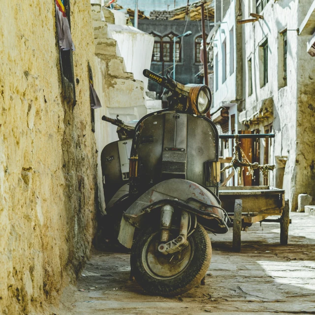 an old motorcycle parked on a narrow street in an alley