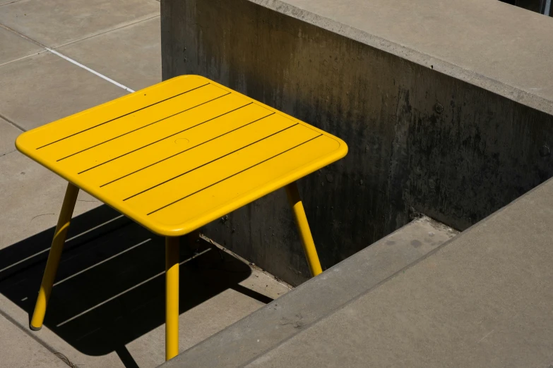 a yellow plastic bench near the wall