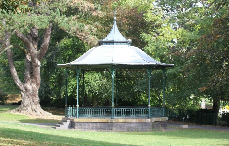 an open gazebo in the middle of some green park grass