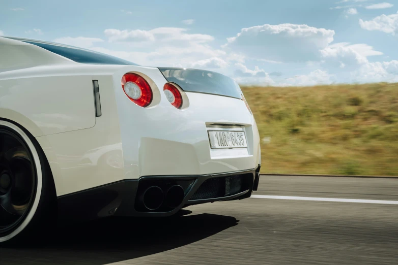 the rear end of a white sports car driving down a road