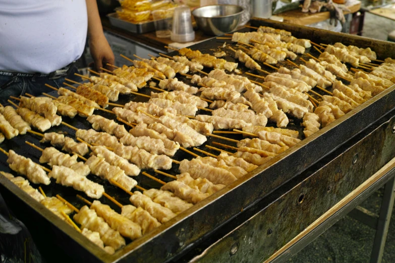 food being prepared on a grill with lots of sticks