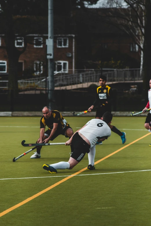 a group of men playing field hockey while one man looks at the ball