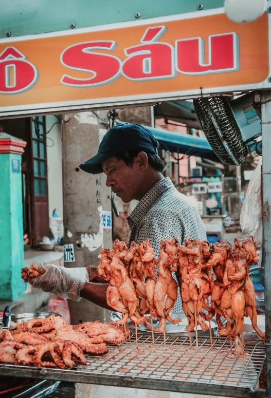 man preparing a bunch of chicken on the grill in the market