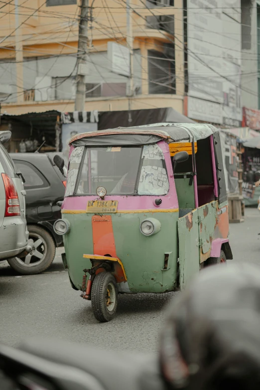 a small green and orange vehicle with a canopy on the street