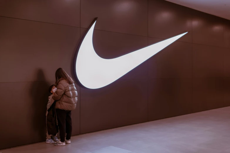 a person stands against a nike logo while taking a po