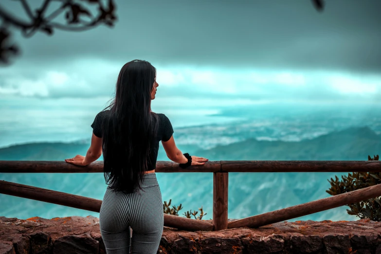 a woman stands on the edge of a cliff looking at a blue ocean