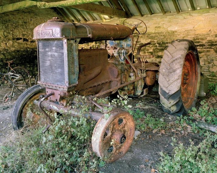 old rusted tractor and hayrow sitting in the grass