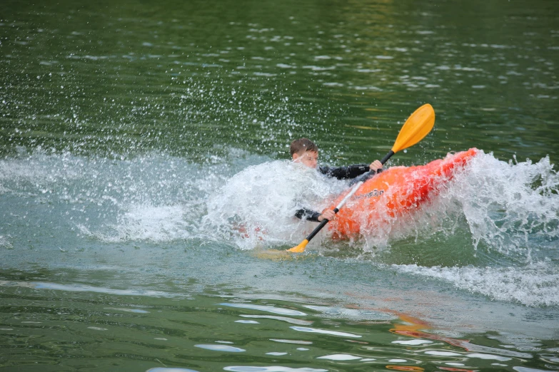 the person is kayaking on the river with splashes of water