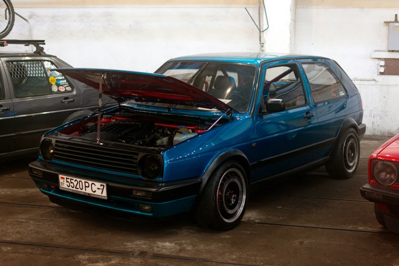 a car with an open hood parked by another car