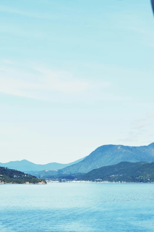 a boat floating in the water with mountains behind it