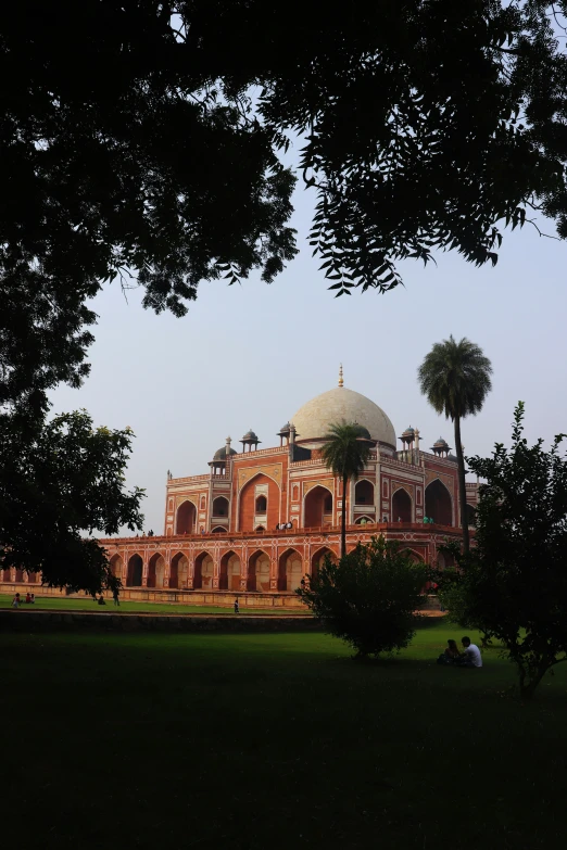 an old building with trees in front and palm trees by it