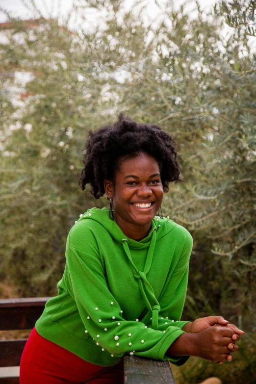 woman in green top smiling and sitting on park bench