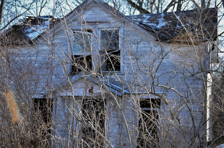 an abandoned white house with broken windows and no doors