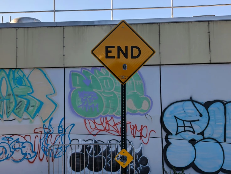 a street sign in front of graffiti covered wall