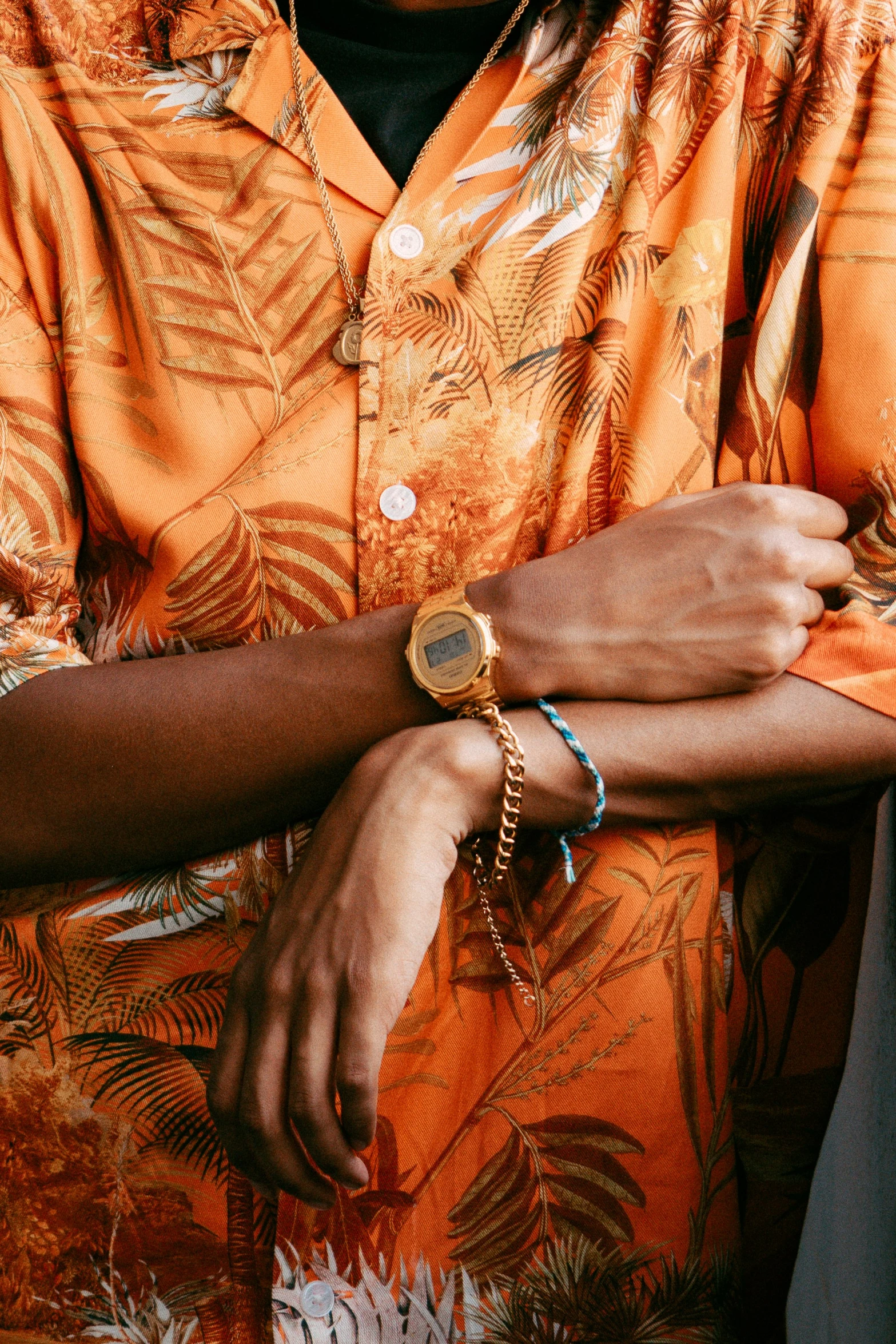 a man with a celet on his wrist and wearing an orange hawaiian shirt