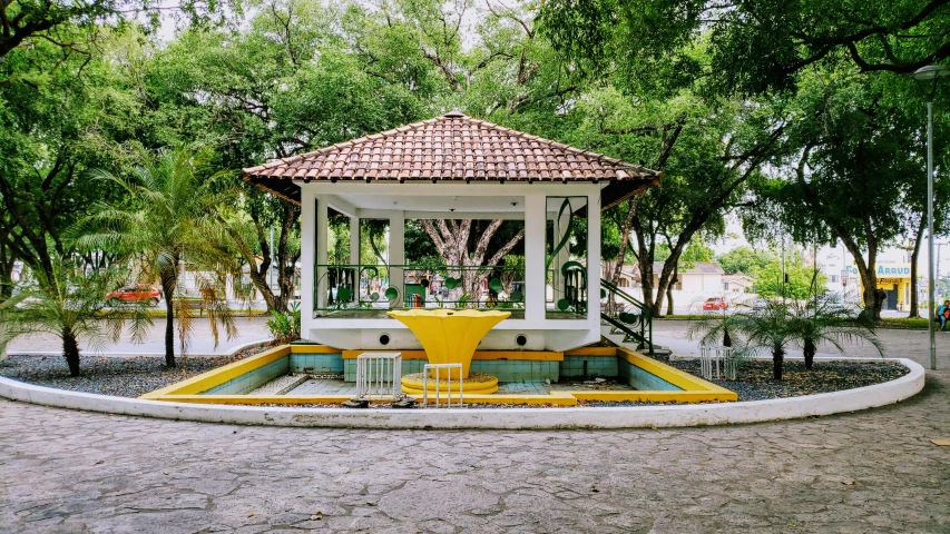 a small white gazebo surrounded by lush green trees