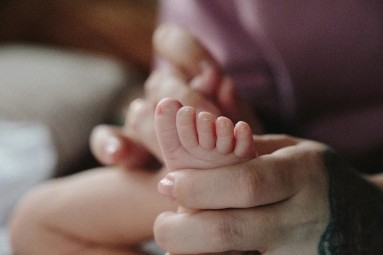 a hand holds out for an infant to touch its face