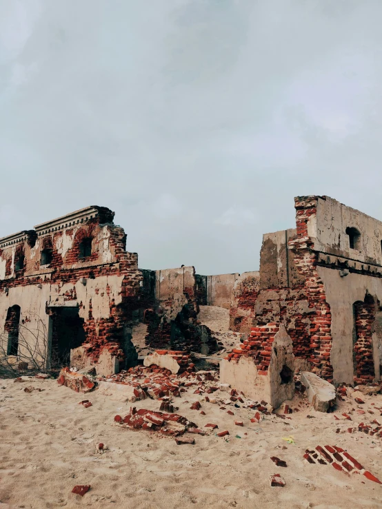 a ruined house sitting on top of a sandy beach