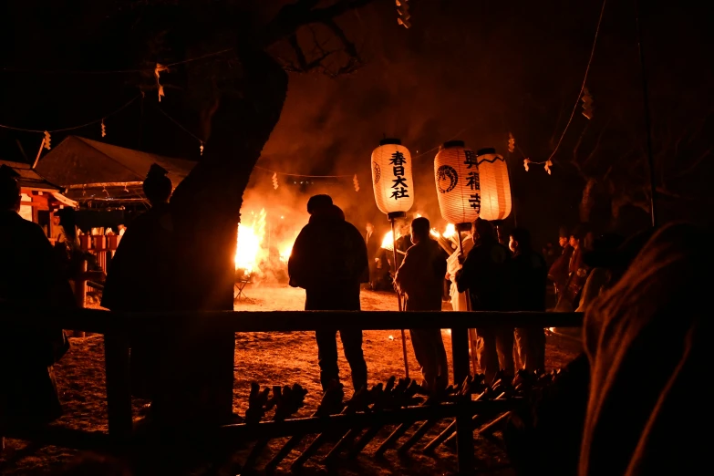 people standing in front of a glowing fire with the dark background