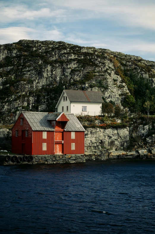 a boat traveling down a body of water next to a red house