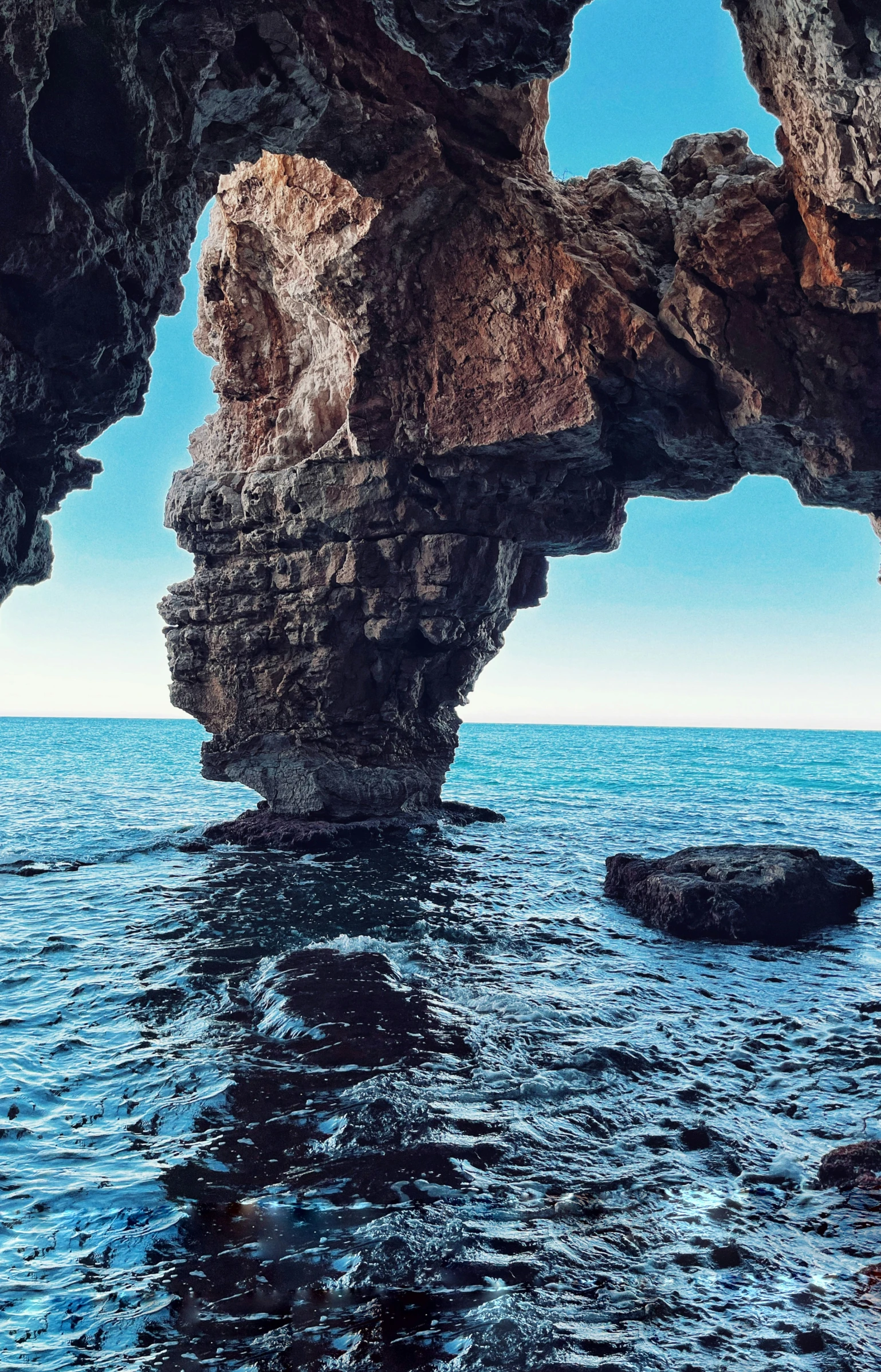 a rock formation in the ocean near a rocky shore