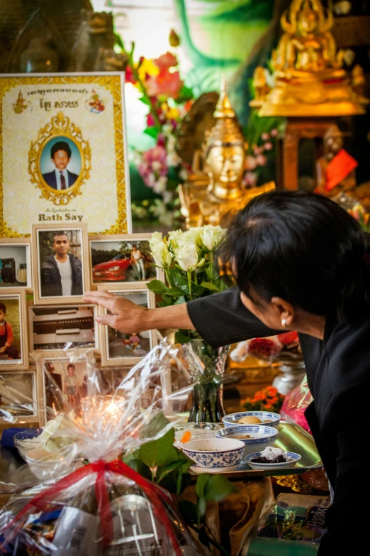 the woman is arranging flowers at the shrine