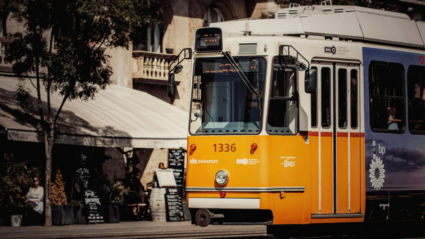 an orange trolley sits on the street beside a curb