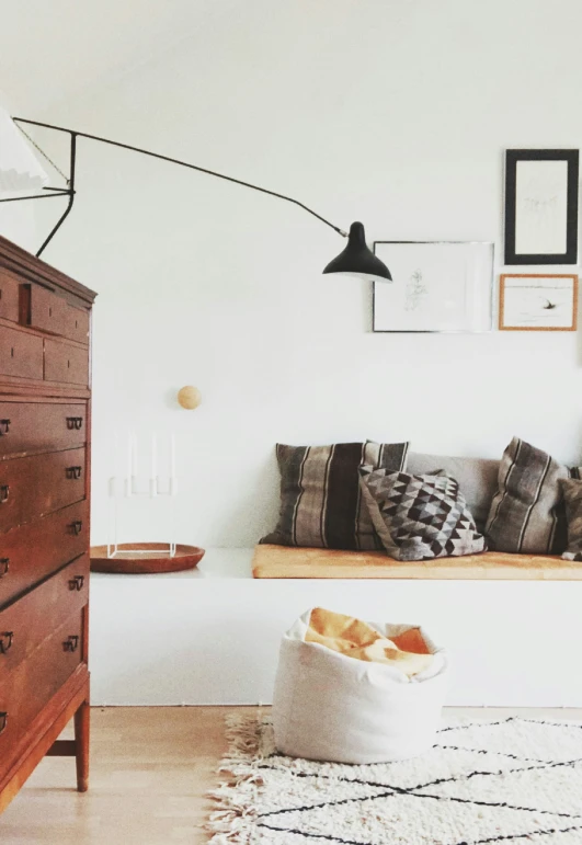 a white room with an oriental rug, chest of drawers and wood furniture