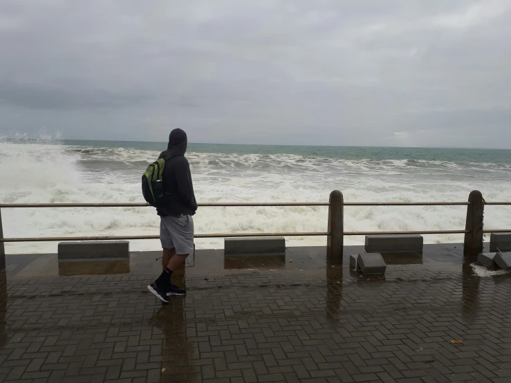 a man standing on the sidewalk looking out over a large body of water