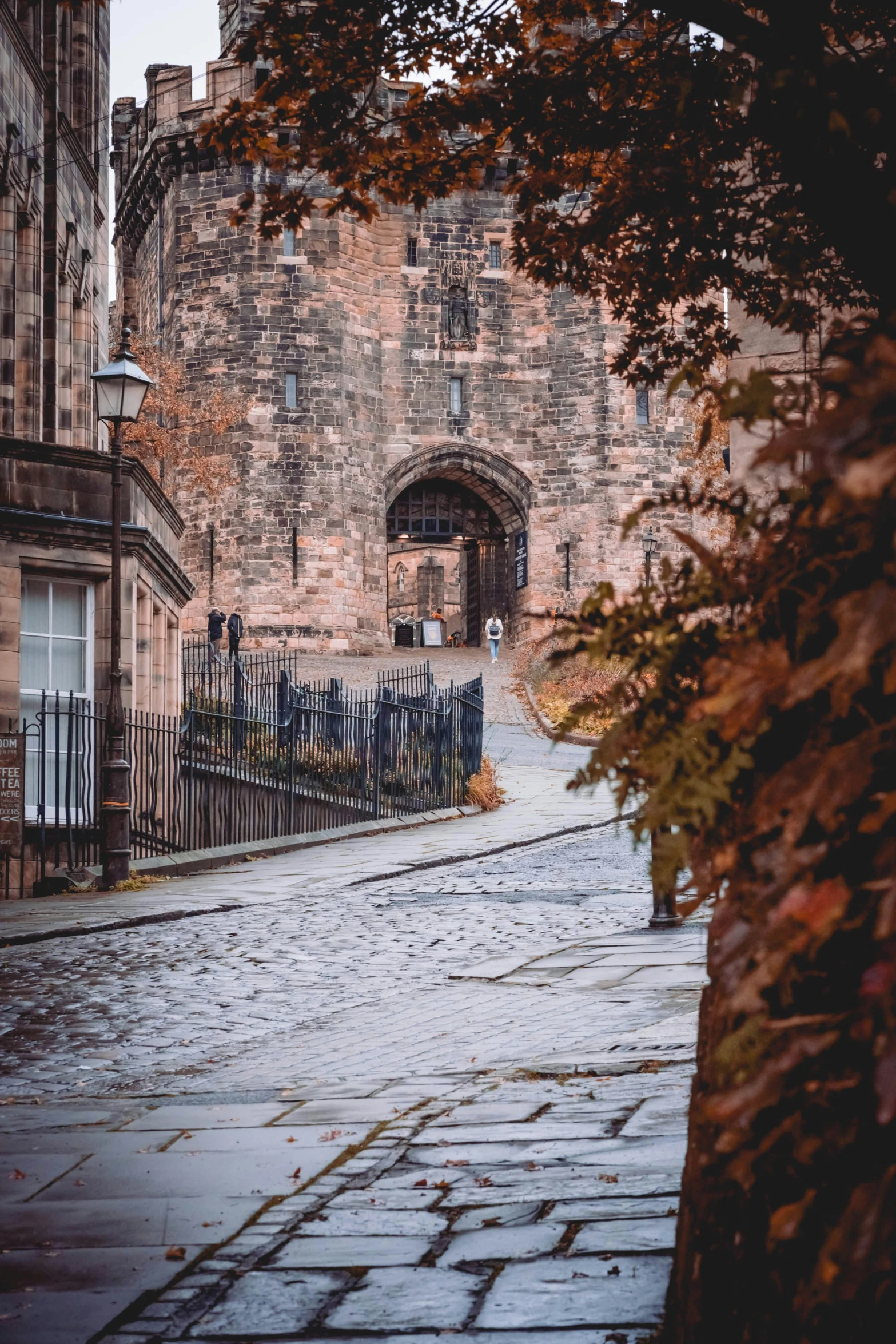 the cobblestone sidewalk is next to a brick building with an archway