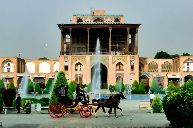 two horses pulling a carriage that has a tower with water coming out