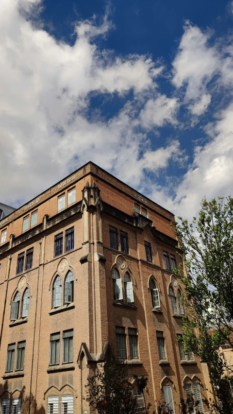 a very old brick building under a cloud filled sky