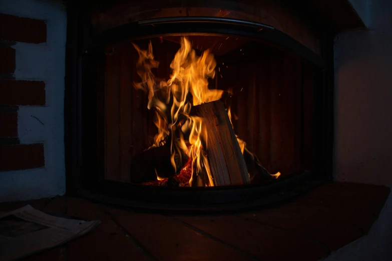 a wood burning in a small fireplace with flames and wood