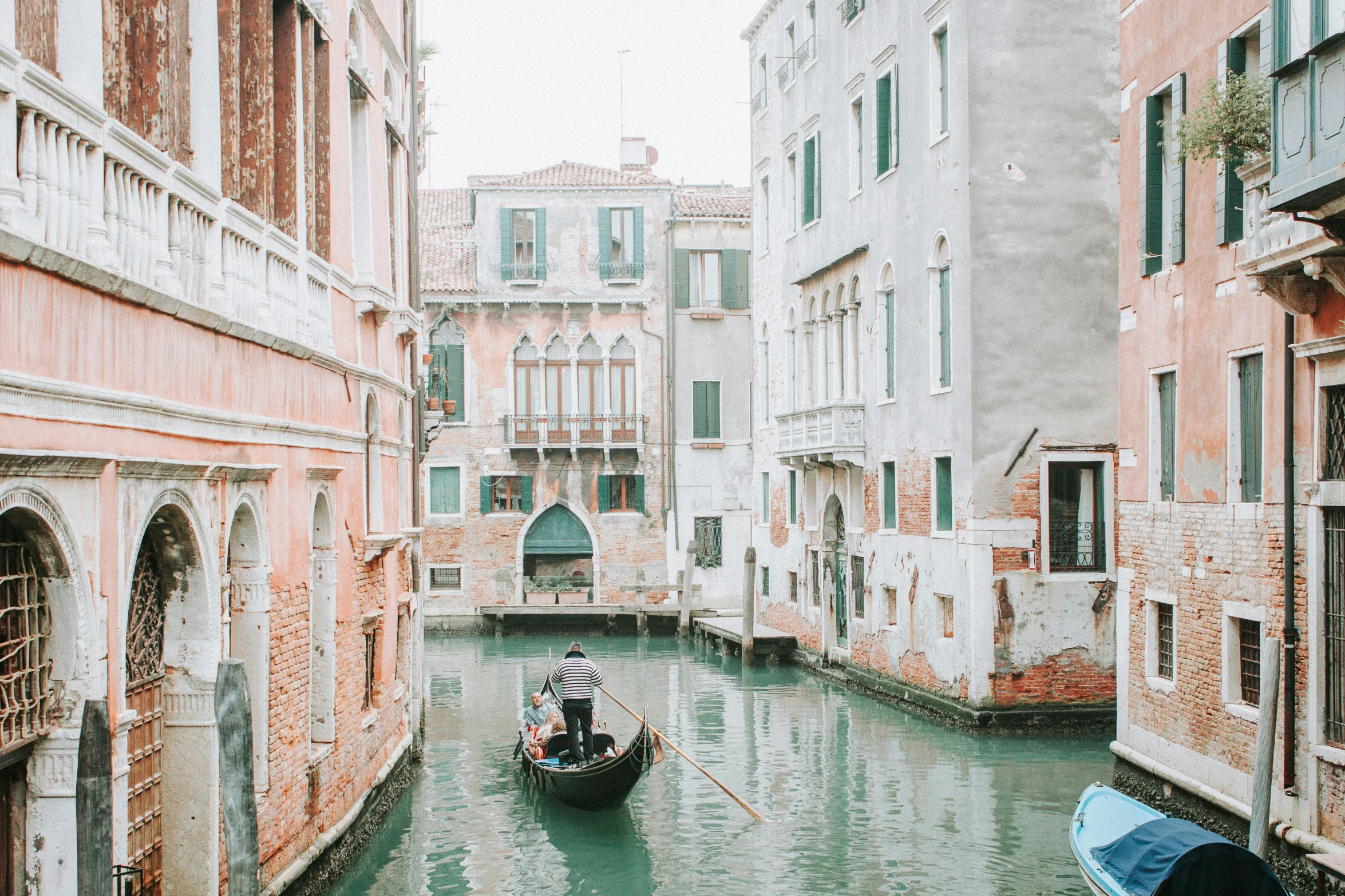 a boat on a river next to a brick building and an archway