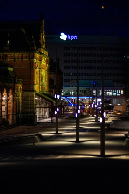 street lamps line the street beside buildings lit up at night