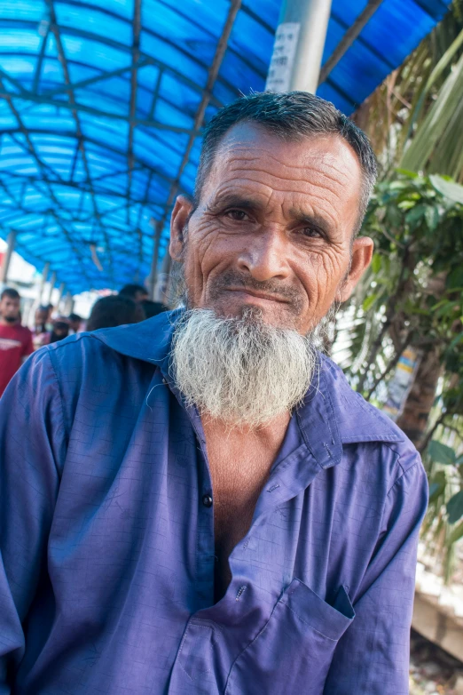 an indian man with a white beard and blue shirt