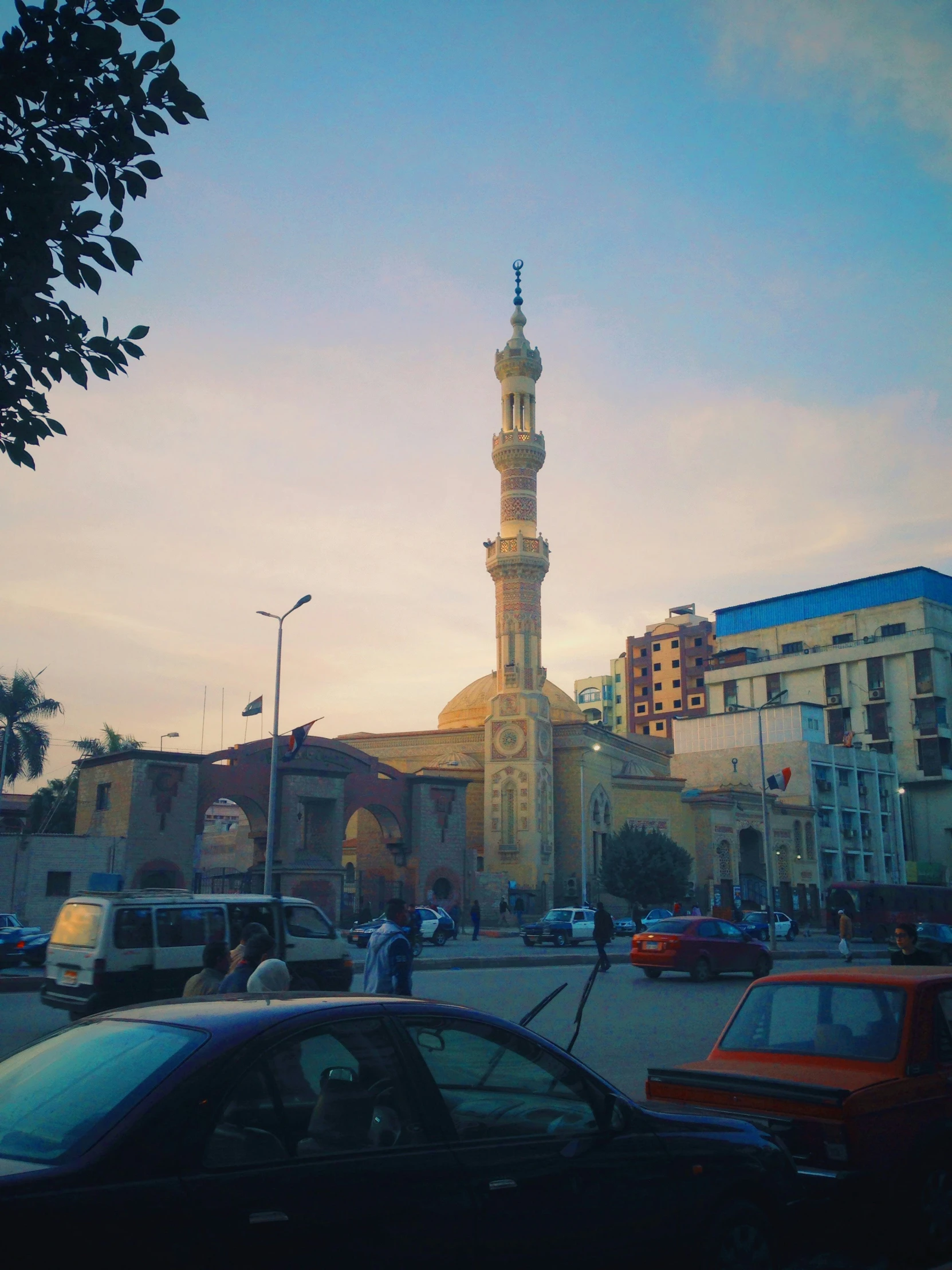 a street with cars, people and a tall tower