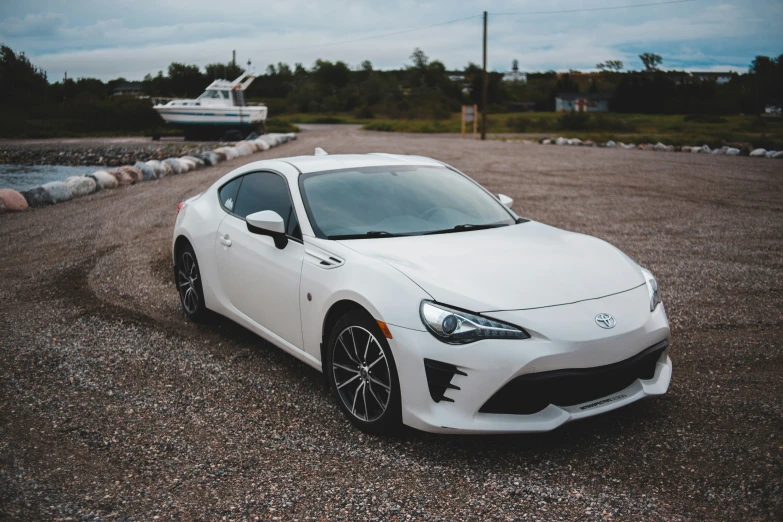 a white car in an empty lot next to a boat