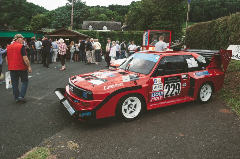 a man walking around a race car in a lot of people