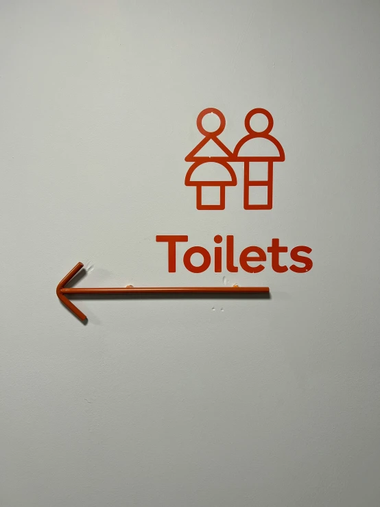 a metal sign mounted on a wall stating toilets