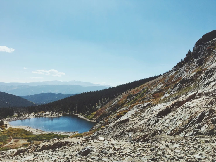 a lake that is near some hills under a blue sky