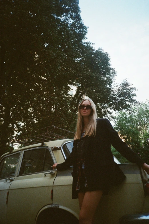 a woman is standing next to a vintage car